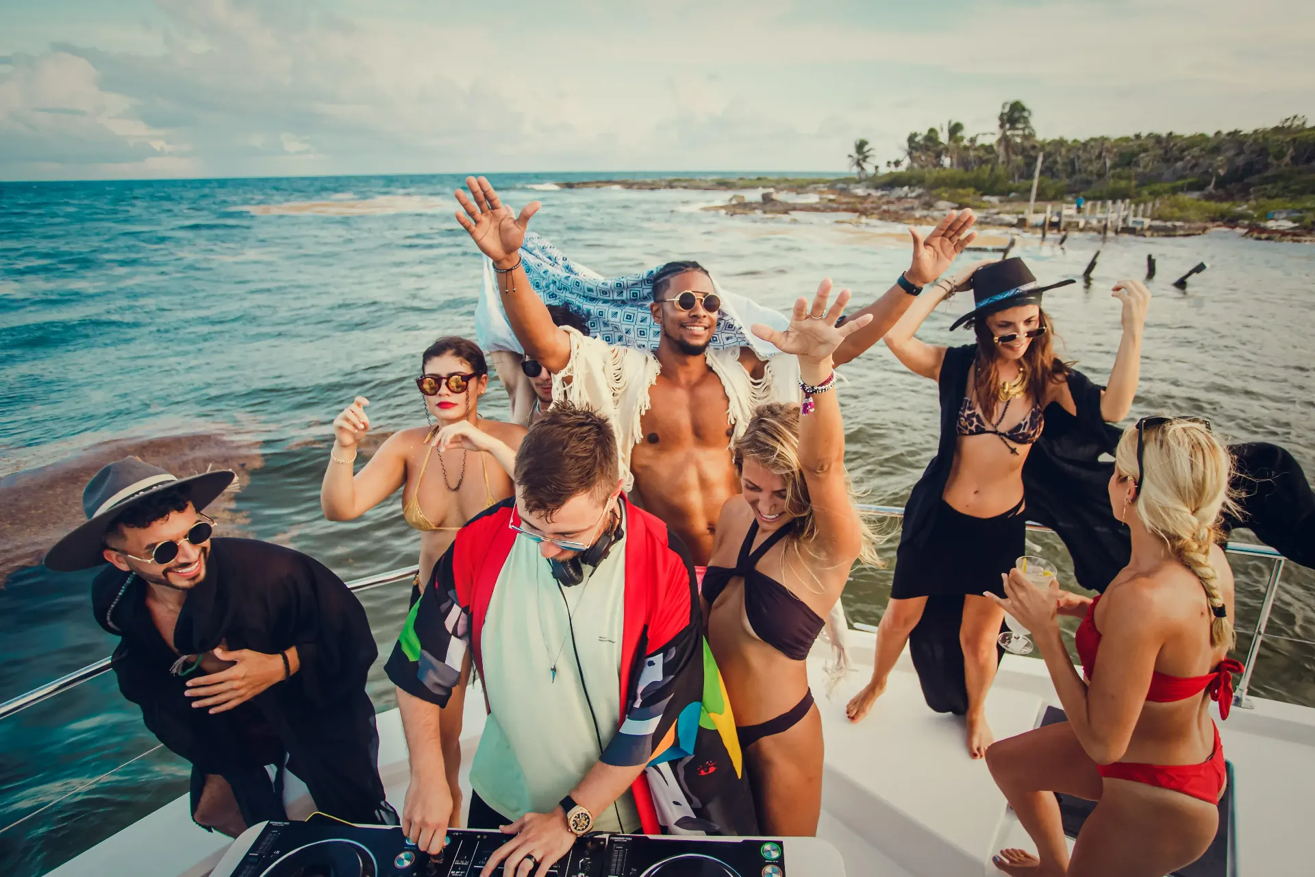 Group of friends celebrating on a catamaran anchored near Cozumel with drinks and musi