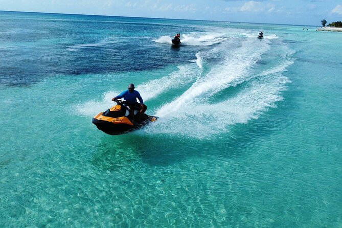 Jet skier speeding across turquoise Caribbean waters with Cozumel coastline and reefs in the background